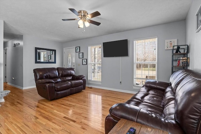 living area with light wood-style floors, a healthy amount of sunlight, baseboards, and a ceiling fan