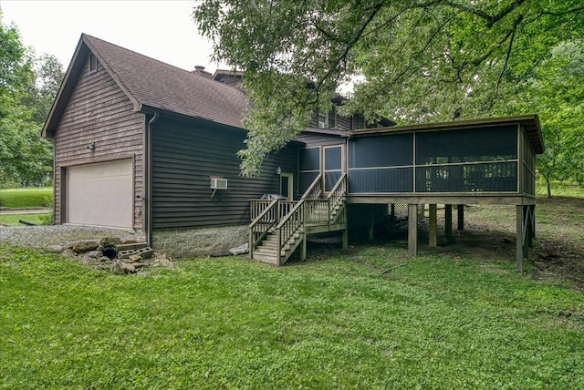 back of property with a garage, a yard, roof with shingles, and a sunroom