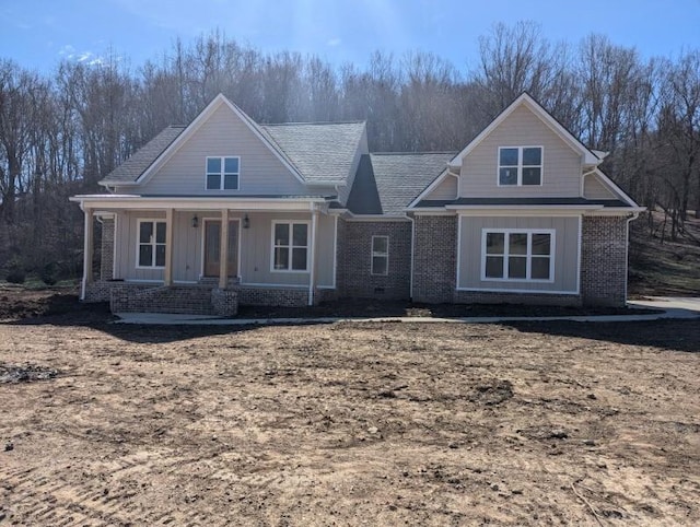 view of front of house with board and batten siding, covered porch, and brick siding