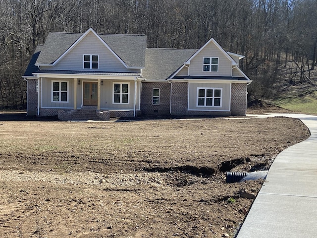 view of front facade featuring brick siding, board and batten siding, and a wooded view