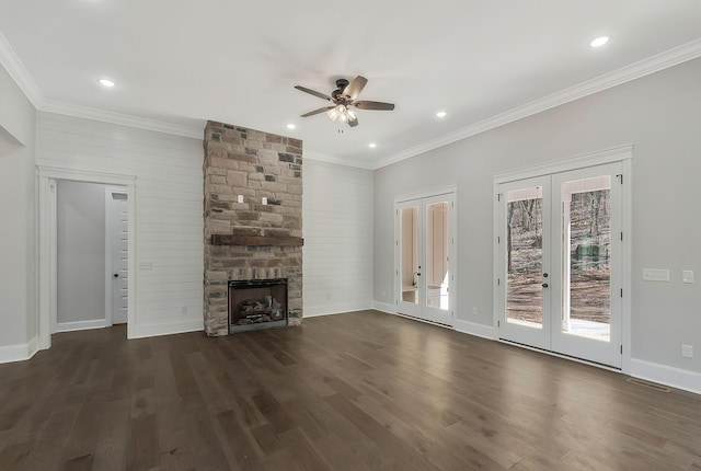 unfurnished living room with ornamental molding, french doors, dark wood finished floors, and a stone fireplace