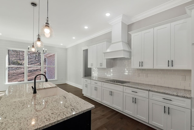 kitchen with dark wood-style floors, black electric cooktop, crown molding, premium range hood, and a sink