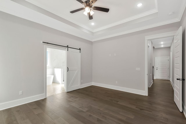 unfurnished bedroom with dark wood-style floors, a barn door, ornamental molding, and baseboards