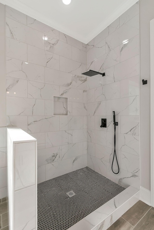 full bathroom with a tile shower, crown molding, and wood finished floors