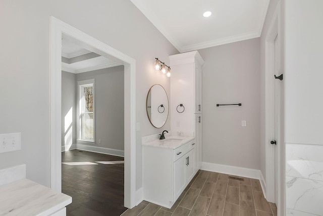 bathroom featuring baseboards, ornamental molding, wood finished floors, and vanity