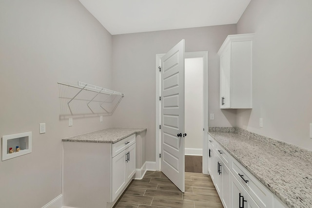 washroom featuring wood tiled floor, washer hookup, cabinet space, and baseboards