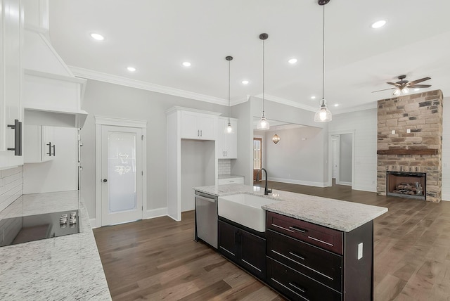 kitchen with white cabinets, black electric cooktop, stainless steel dishwasher, a fireplace, and a sink