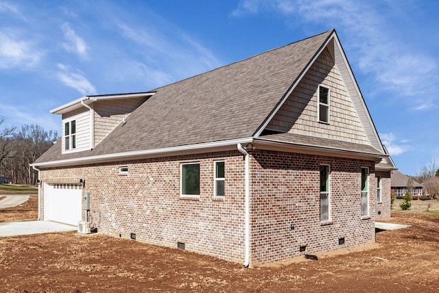 view of home's exterior with roof with shingles, brick siding, crawl space, and driveway