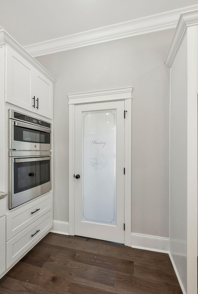 interior space with baseboards, dark wood-type flooring, and crown molding