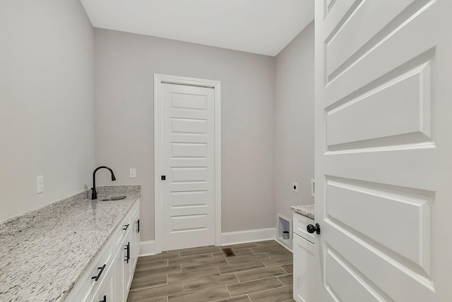 laundry room featuring wood finish floors, a sink, electric dryer hookup, and baseboards