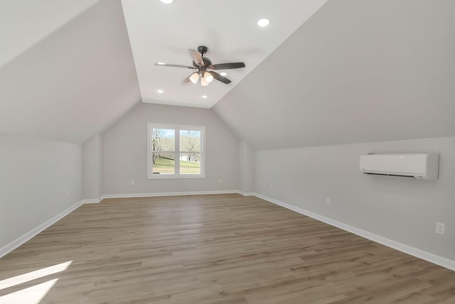 bonus room with vaulted ceiling, a wall unit AC, baseboards, and light wood-style floors