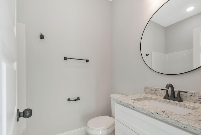 bathroom featuring toilet, baseboards, and vanity