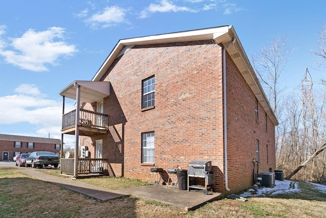 view of home's exterior featuring a balcony, a patio area, cooling unit, and brick siding