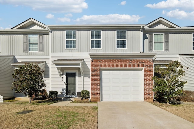 townhome / multi-family property featuring a garage, concrete driveway, and brick siding