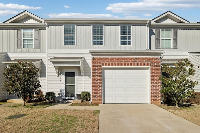 view of property with driveway, a garage, and brick siding