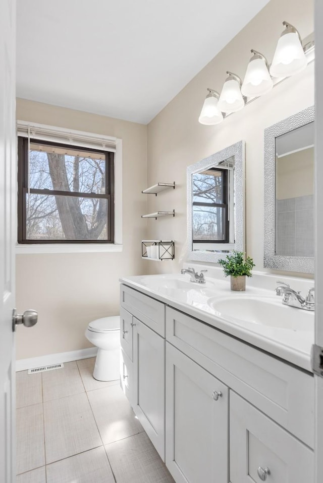 bathroom featuring toilet, tile patterned flooring, double vanity, and a sink