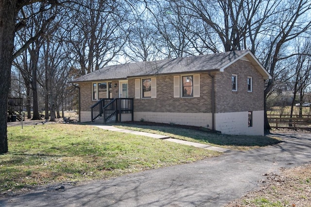 ranch-style home featuring brick siding, a front lawn, and fence