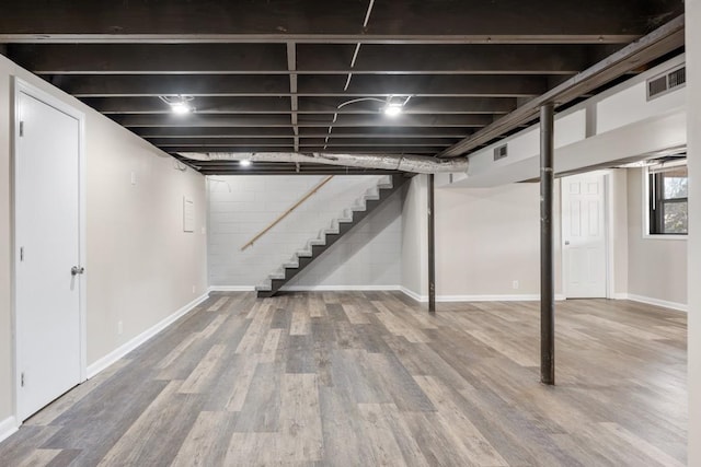 below grade area with wood finished floors, visible vents, baseboards, and stairs