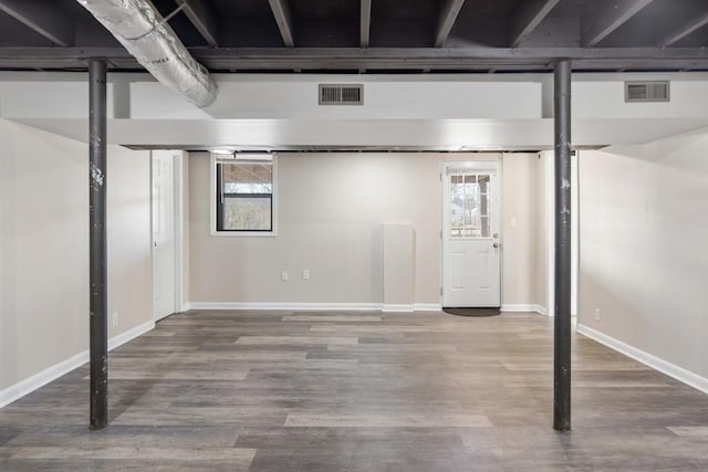 basement with a wealth of natural light, visible vents, and wood finished floors