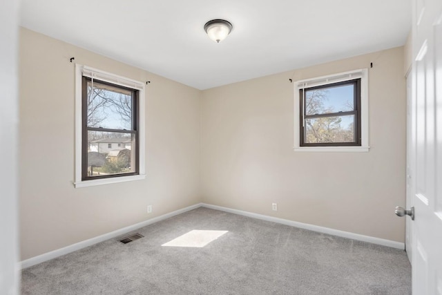 empty room with carpet, plenty of natural light, visible vents, and baseboards