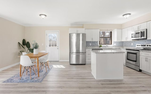 kitchen featuring stainless steel appliances, a kitchen island, a wealth of natural light, and decorative backsplash