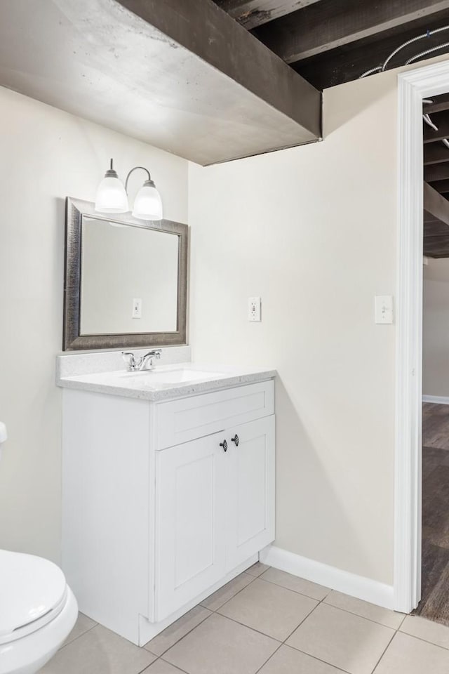 half bathroom featuring tile patterned flooring, baseboards, vanity, and toilet