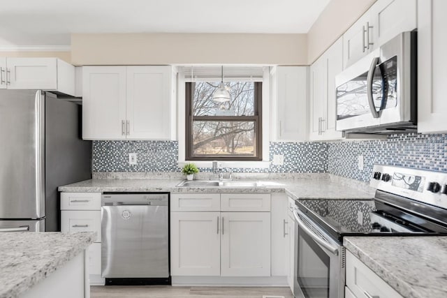 kitchen with light wood finished floors, decorative backsplash, appliances with stainless steel finishes, white cabinetry, and a sink