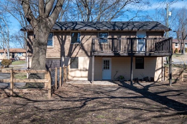 rear view of house with brick siding, fence, and a wooden deck