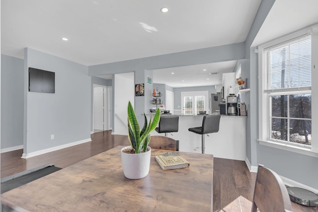 dining space with baseboards, wood finished floors, and recessed lighting