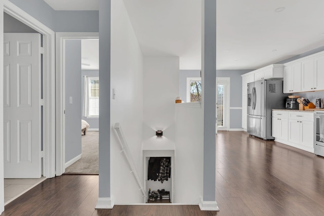 interior space featuring white cabinets, baseboards, stainless steel appliances, and dark wood-type flooring