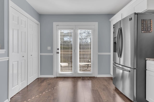 kitchen with light stone counters, dark wood-style flooring, white cabinetry, baseboards, and stainless steel fridge with ice dispenser