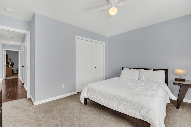 bedroom with a ceiling fan, baseboards, dark colored carpet, and a closet