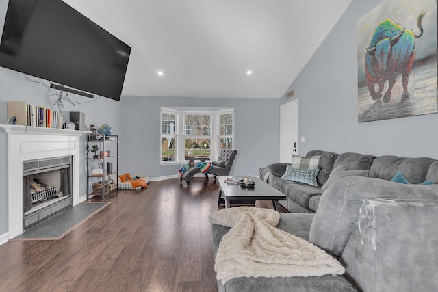 living area featuring dark wood finished floors, lofted ceiling, recessed lighting, a fireplace with raised hearth, and baseboards