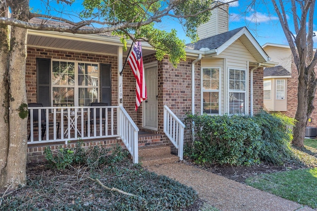 view of front of home with covered porch, roof with shingles, a chimney, and brick siding