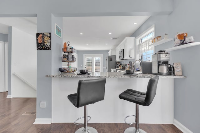 kitchen with a peninsula, a healthy amount of sunlight, white cabinetry, and a kitchen breakfast bar