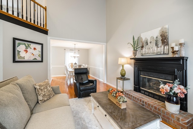 living room with baseboards, a glass covered fireplace, a towering ceiling, and light wood-style floors