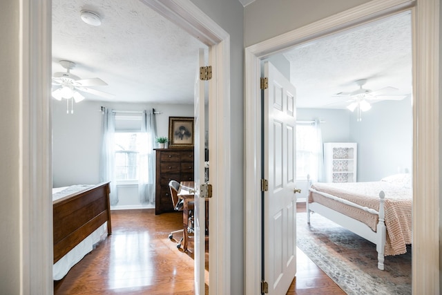 bedroom with dark wood-style floors, multiple windows, a textured ceiling, and a ceiling fan