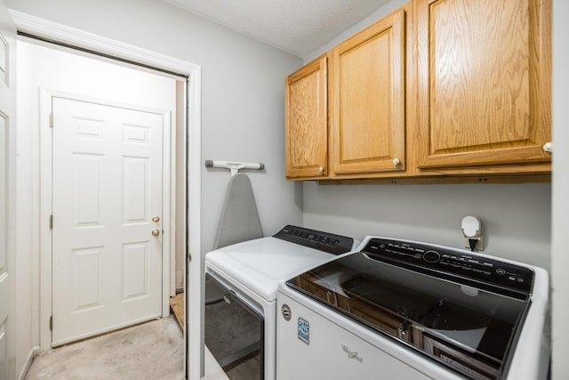 laundry room featuring washing machine and dryer, cabinet space, and a textured ceiling