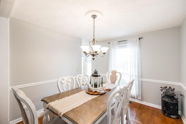 dining area with a chandelier, dark wood finished floors, and baseboards