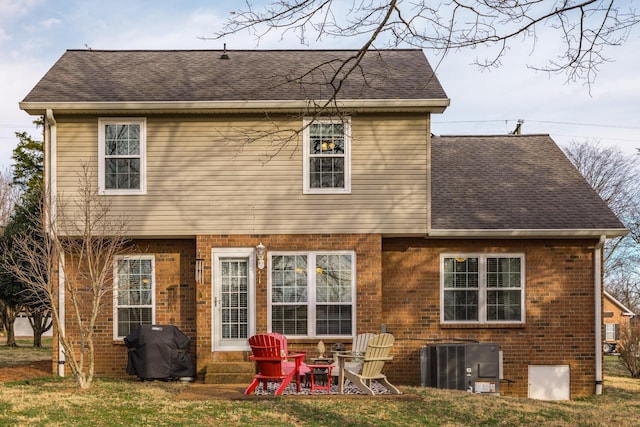 back of house with a yard, brick siding, and central air condition unit