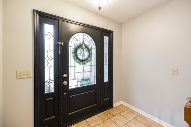 entryway with a textured ceiling, light tile patterned flooring, and baseboards