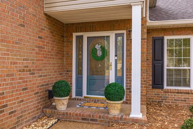 property entrance with roof with shingles and brick siding