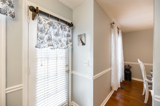 doorway with dark wood finished floors and baseboards