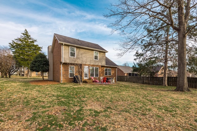 back of property with brick siding, a lawn, a patio area, and fence