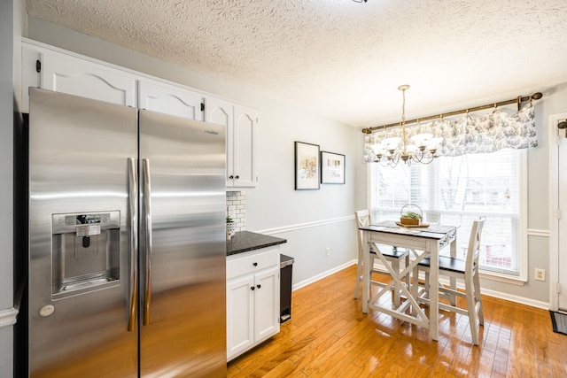 kitchen with pendant lighting, light wood finished floors, white cabinetry, and stainless steel fridge with ice dispenser