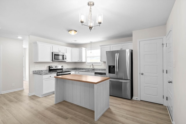 kitchen featuring appliances with stainless steel finishes, white cabinets, and pendant lighting