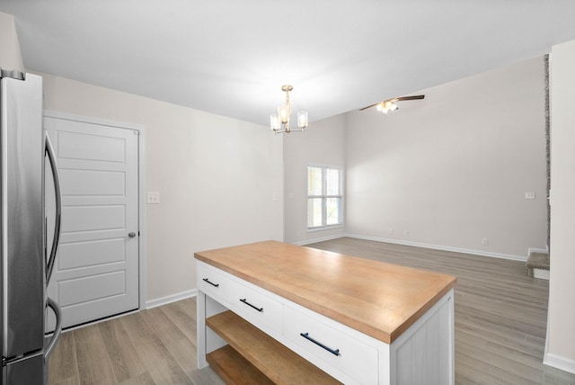 kitchen with open floor plan, freestanding refrigerator, light wood-style floors, white cabinetry, and pendant lighting