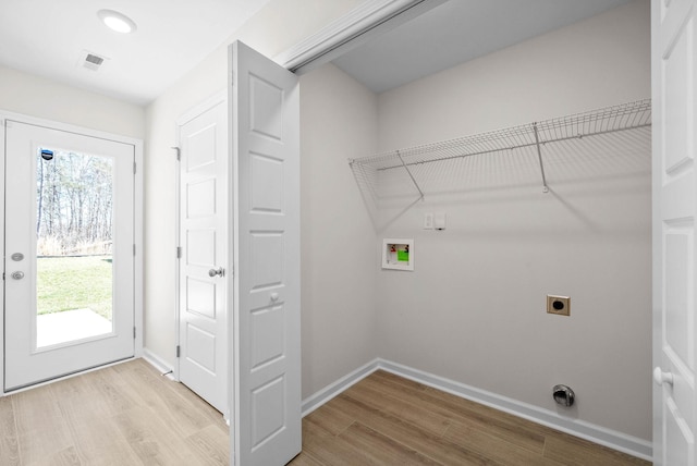 clothes washing area with a healthy amount of sunlight, laundry area, light wood-style flooring, and electric dryer hookup