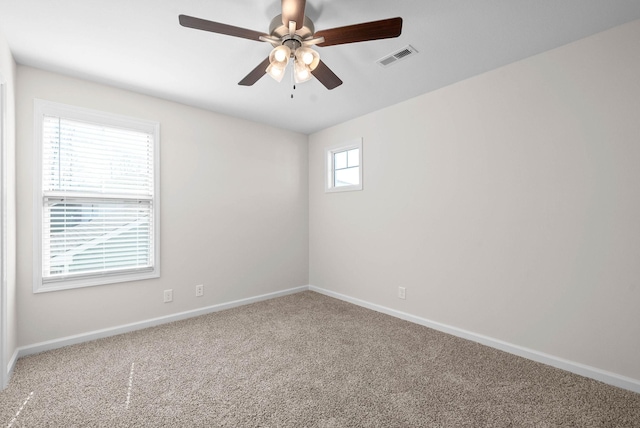 spare room with carpet floors, visible vents, ceiling fan, and baseboards