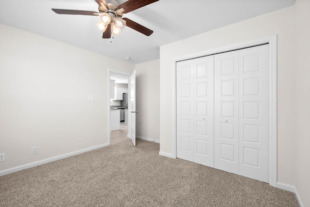 unfurnished bedroom with light carpet, ceiling fan, a closet, and baseboards